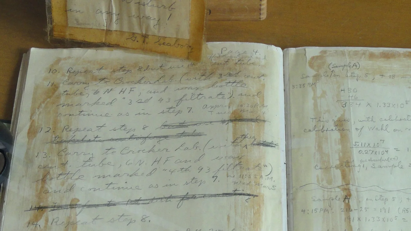An open, handwritten laboratory notebook with stained pages