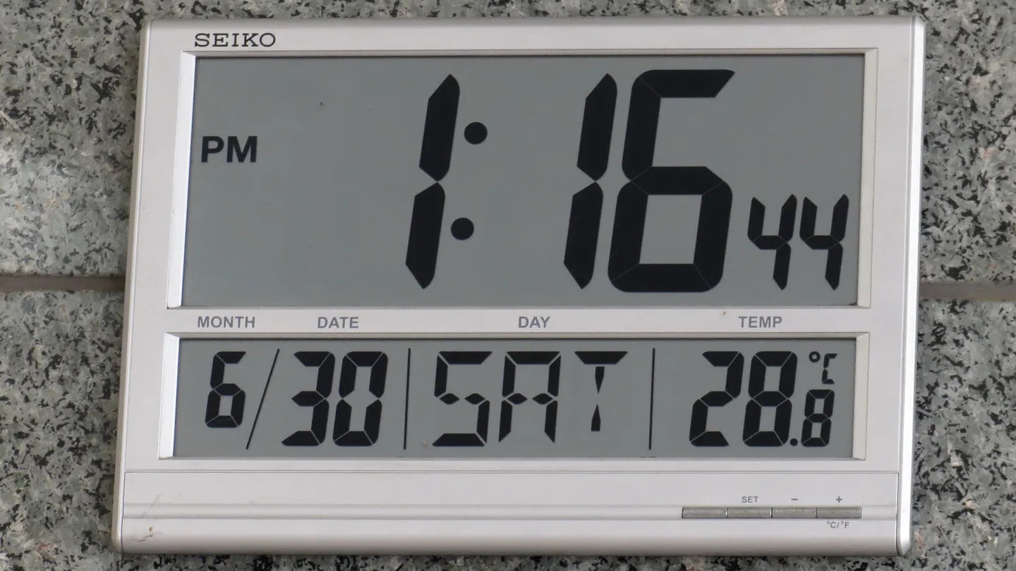 A Seiko digital wall clock showing the time, date and temperature